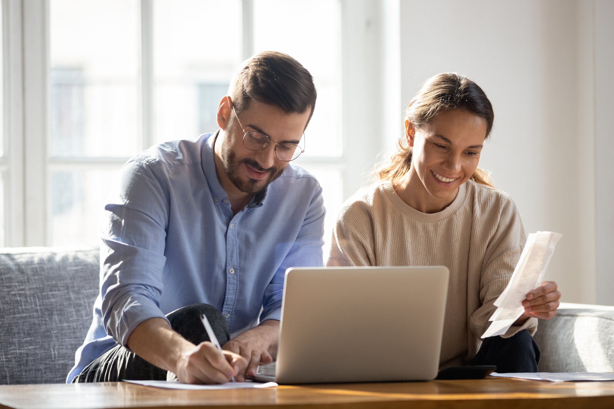 Smiling couple using laptop and taking notes