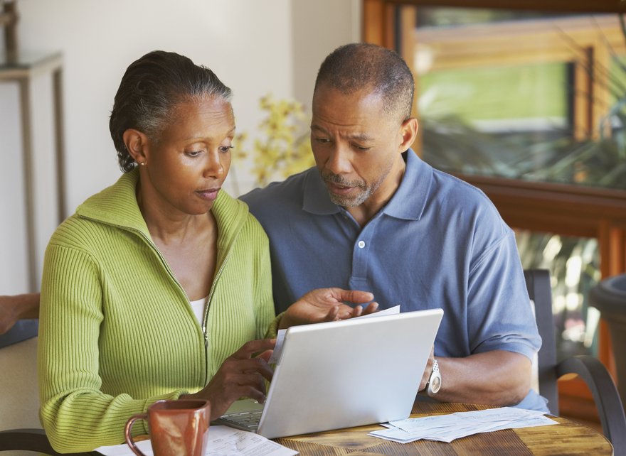 Two people review documents in front of a laptop at home.