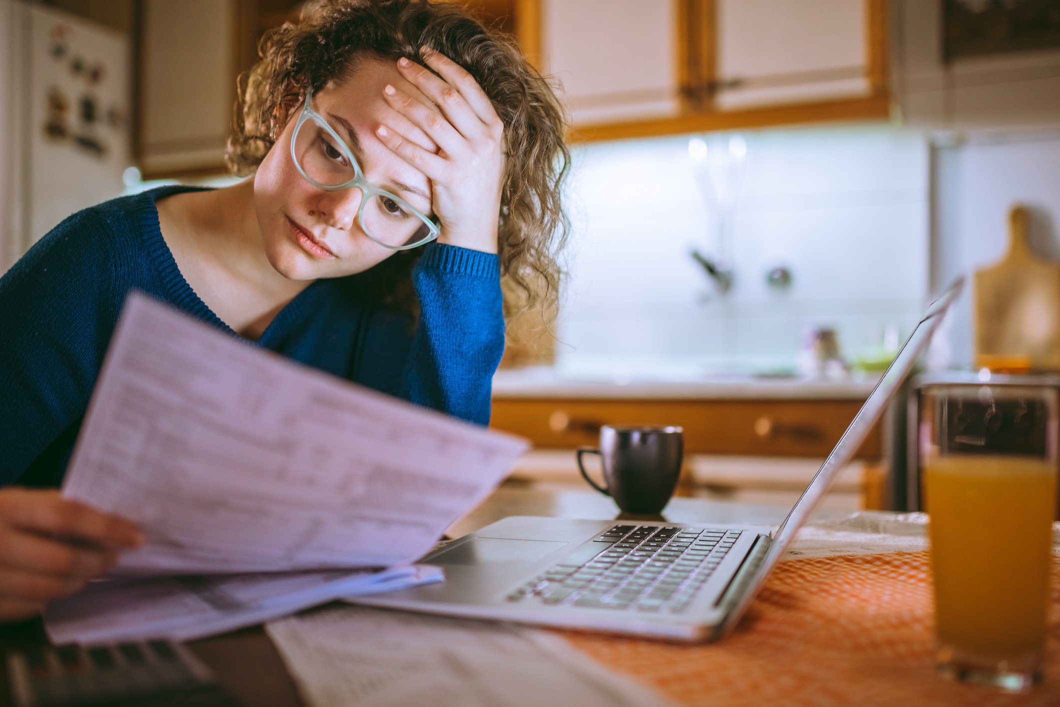 Stressed young woman in glasses looking at bill