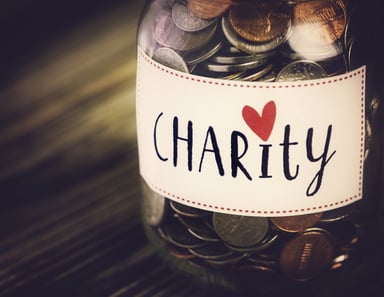 Glass jar filled with coins labeled Charity