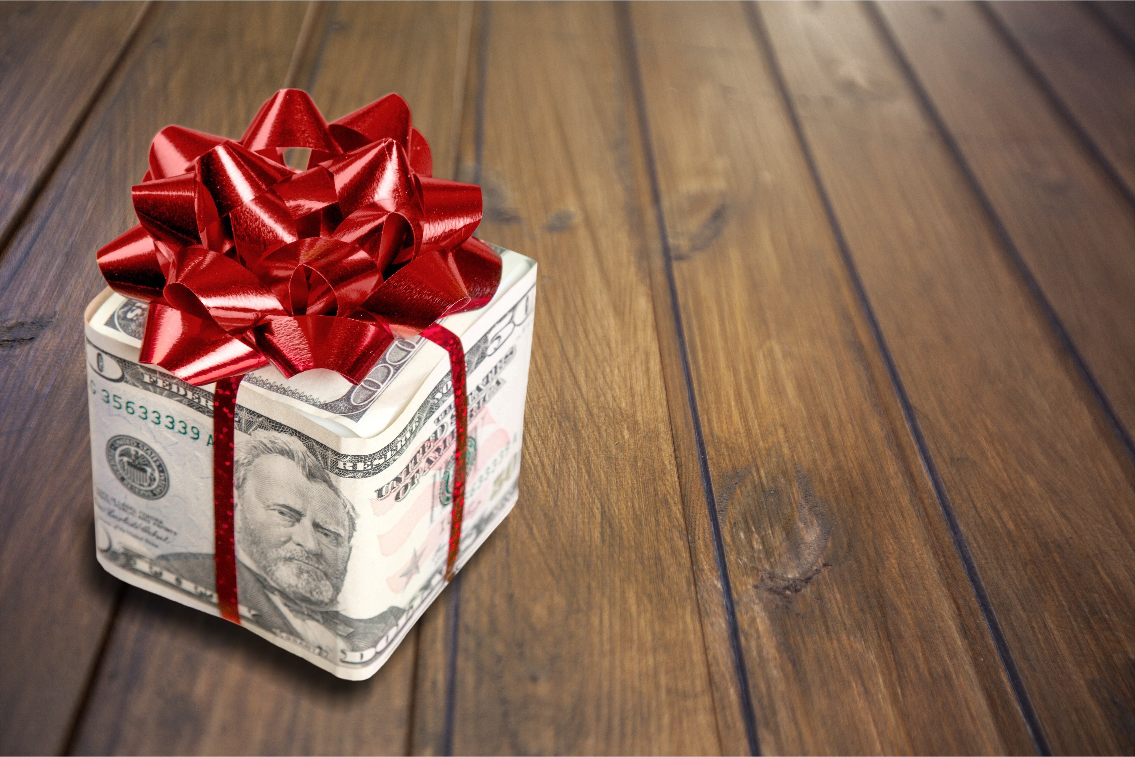 A gift box wrapped in money and a bow