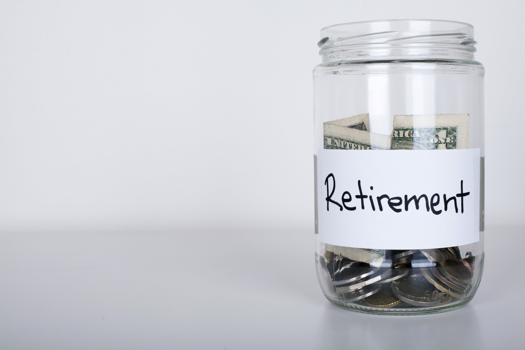 jar labeled retirement and half-filled with cash and coins