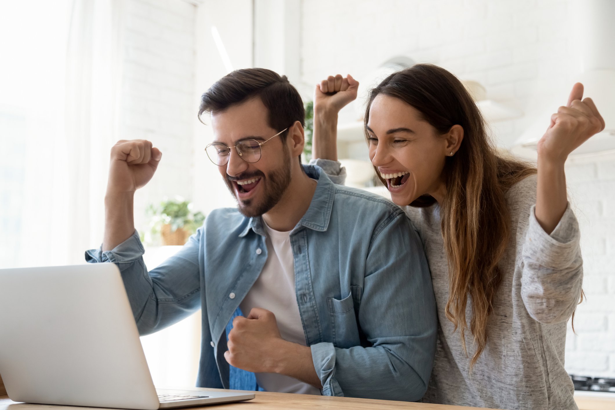 Couple cheering in front of laptop