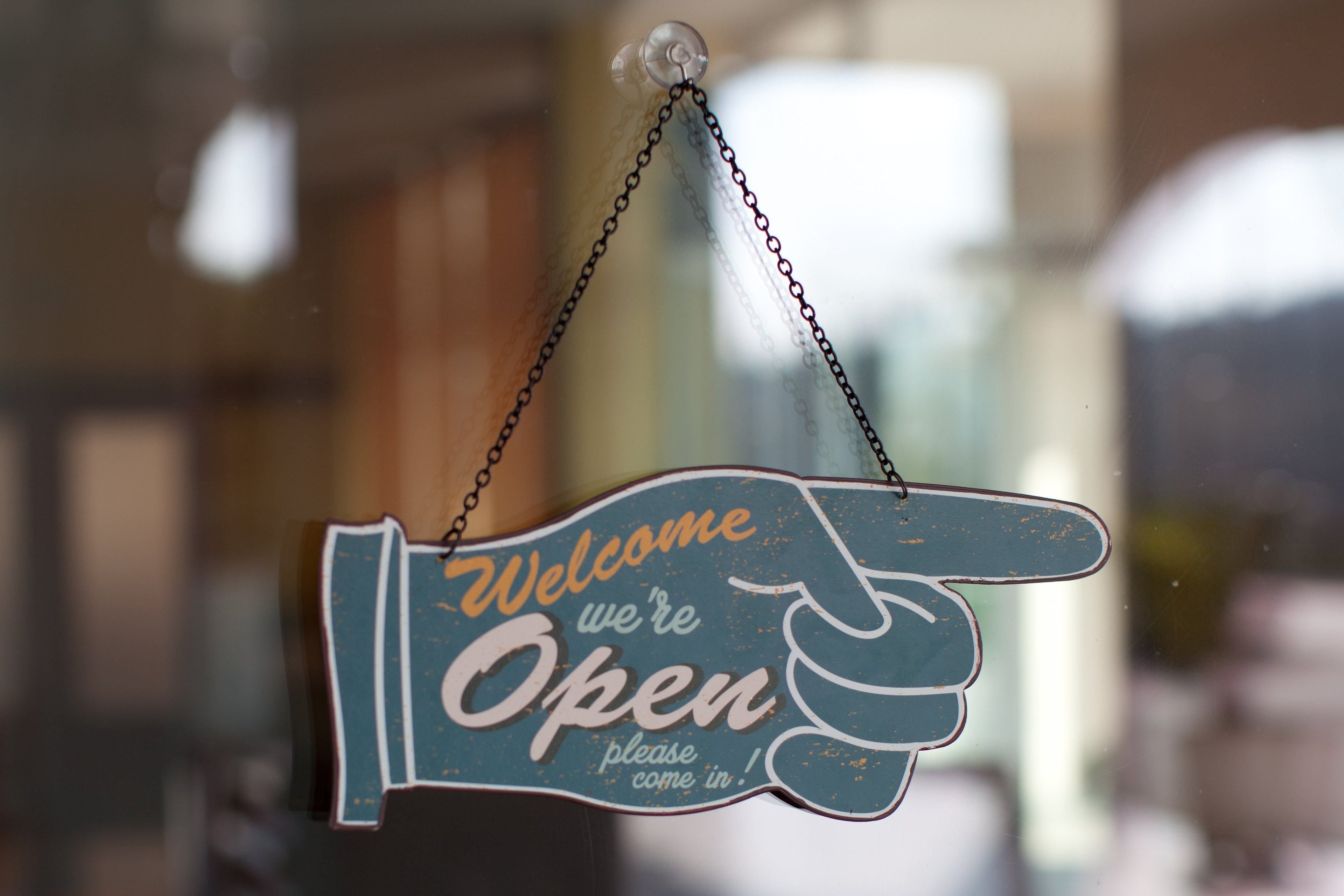 A store sign reading Welcome we are open.