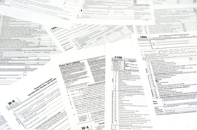 A pile of scattered tax forms that includes a W-9 and W-4.