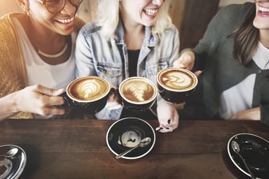 Three women drinking coffees in a coffee shop.
