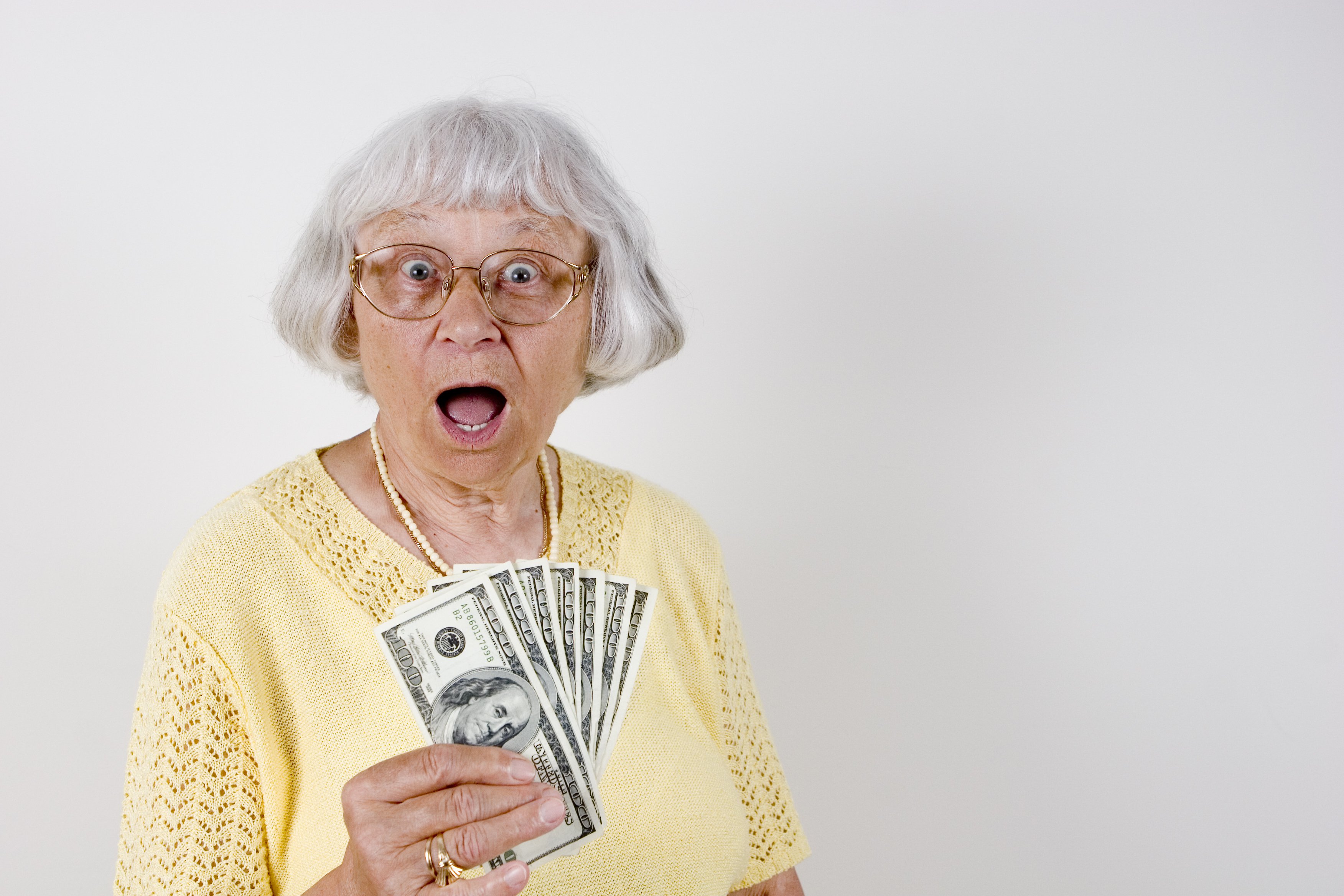older woman with surprised expression, holding cash