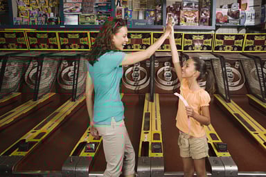 mom and daughter high-fave in arcade