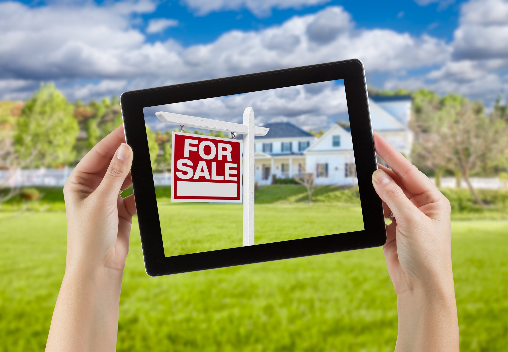 House for sale seen through frame of a tablet