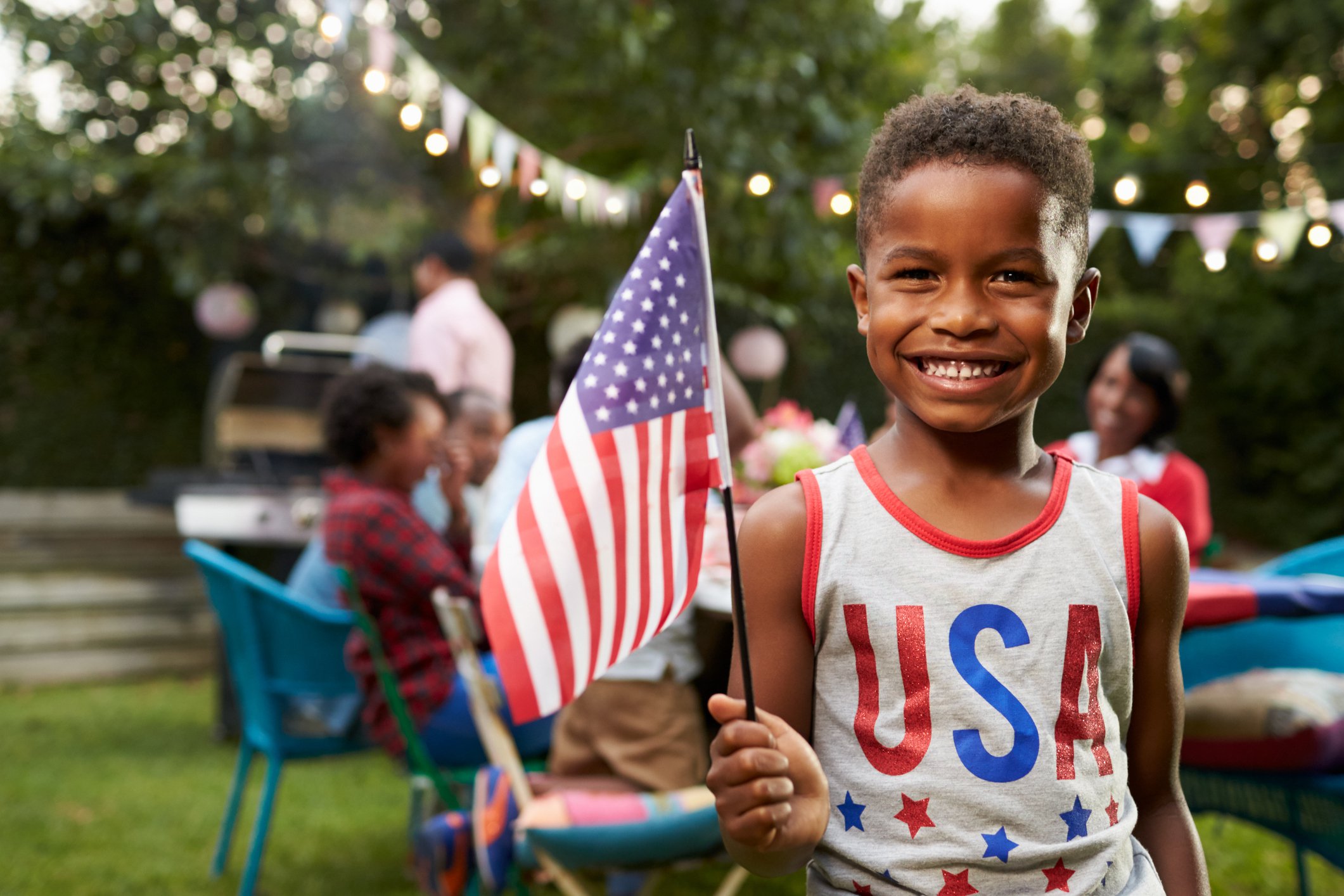Young boy wearing USA tank top and holding American flag