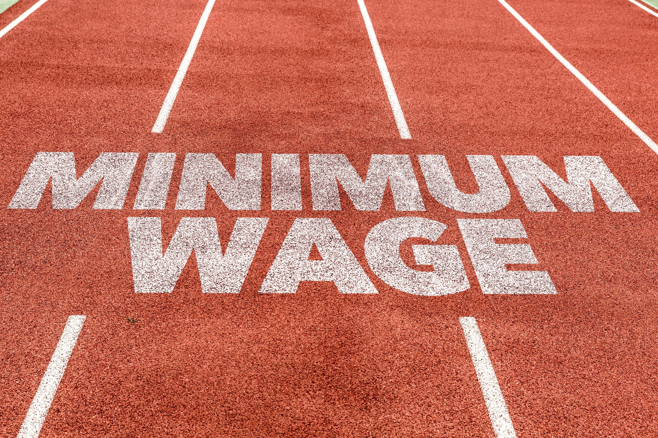 The words Minimum Wage written in white paint on a red track field