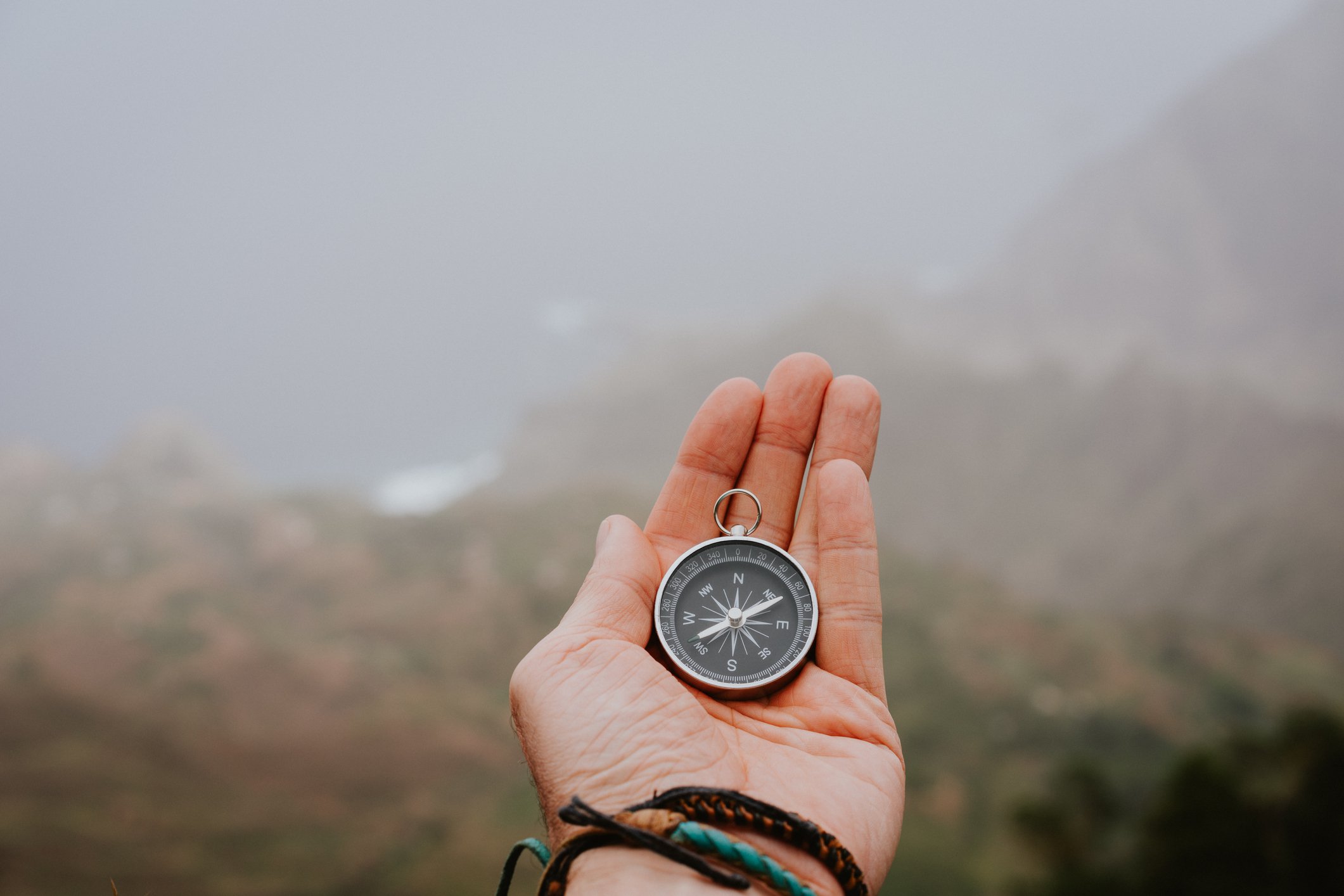 Person holding compass in hands outdoors.