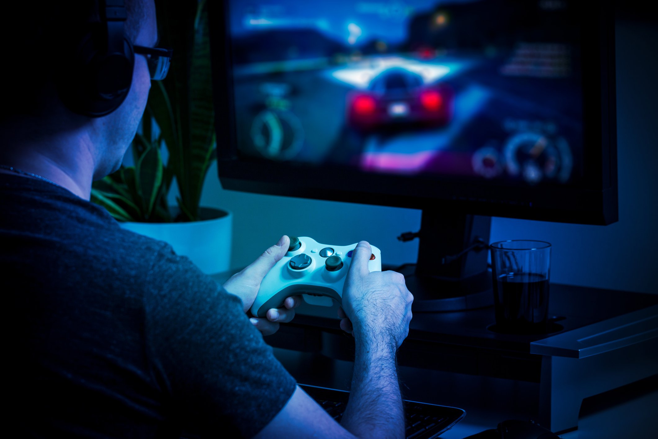 A man plays a video game in a darkened room.