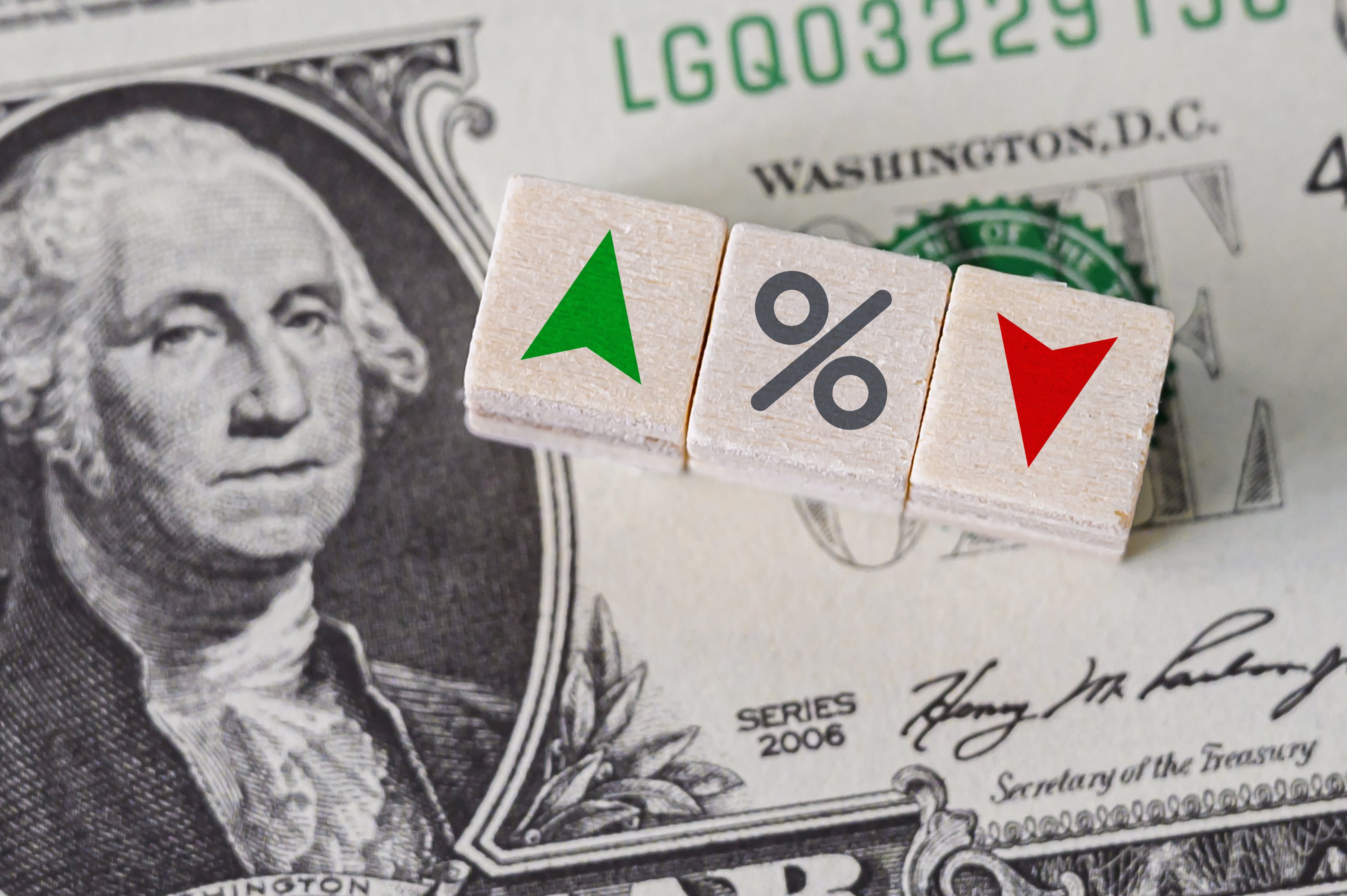 Depiction of interest rates with dollar bill and blocks with up and down arrows and percent symbol