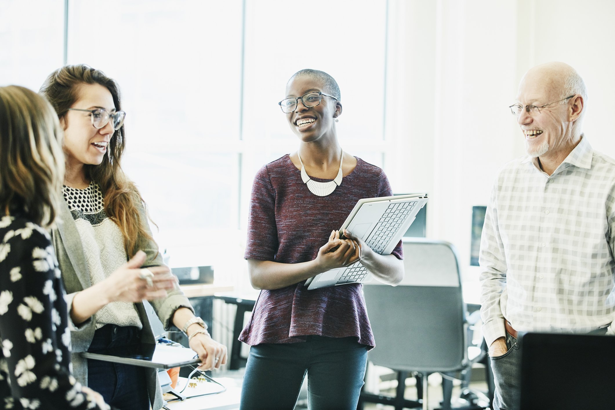 Co-workers smiling and standing together in an office