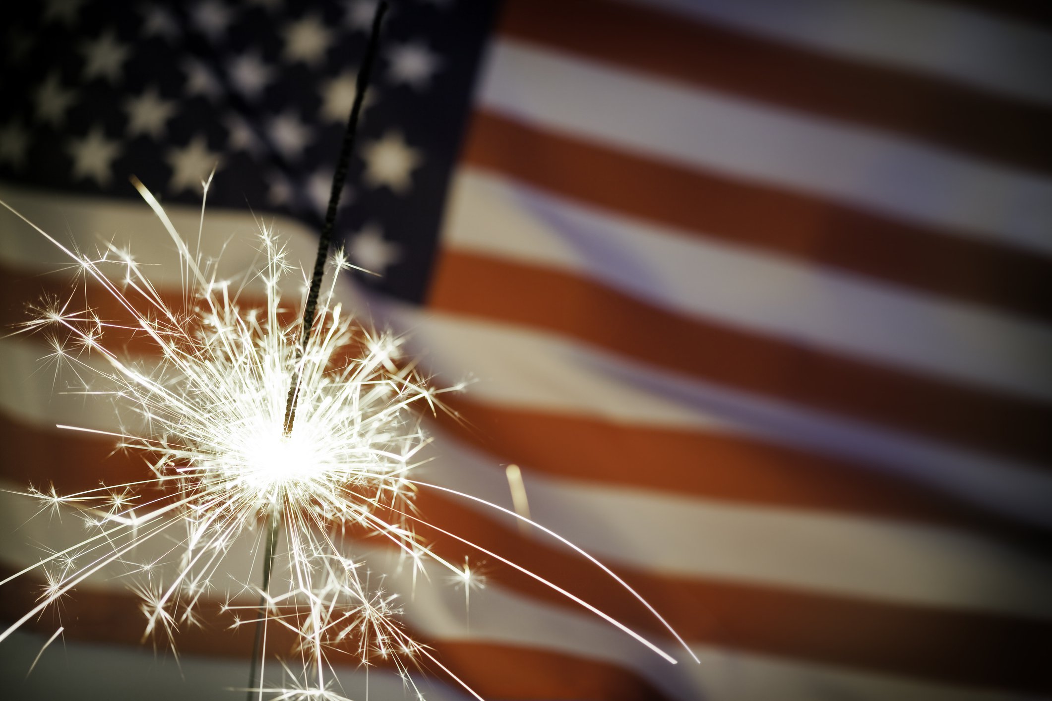 US flag with sparkler in front of it.