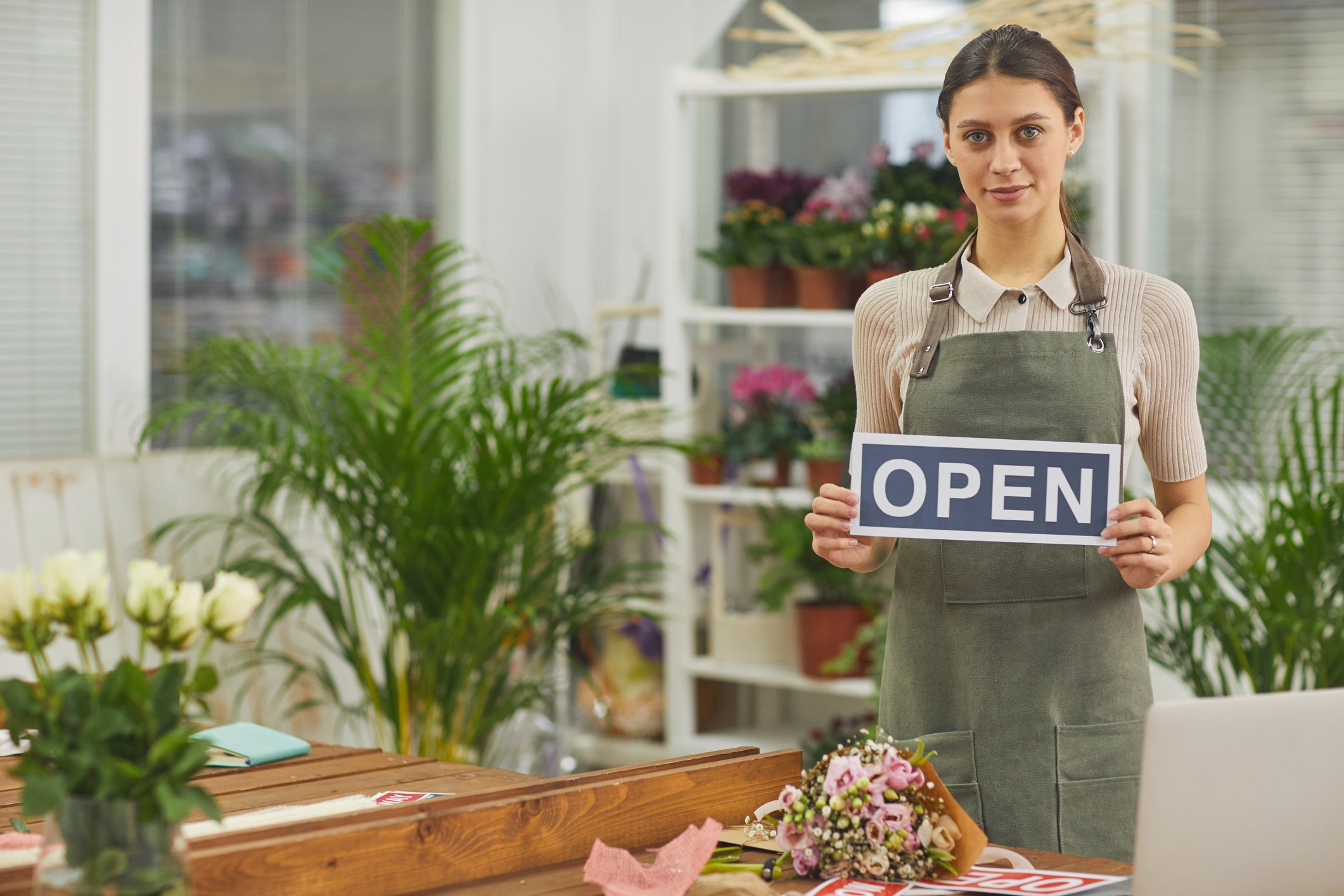 Worker in floral shop holding open sign