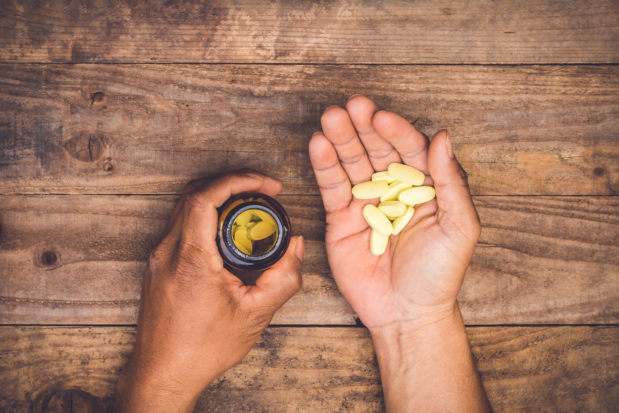 Hands holding some pills from a bottle