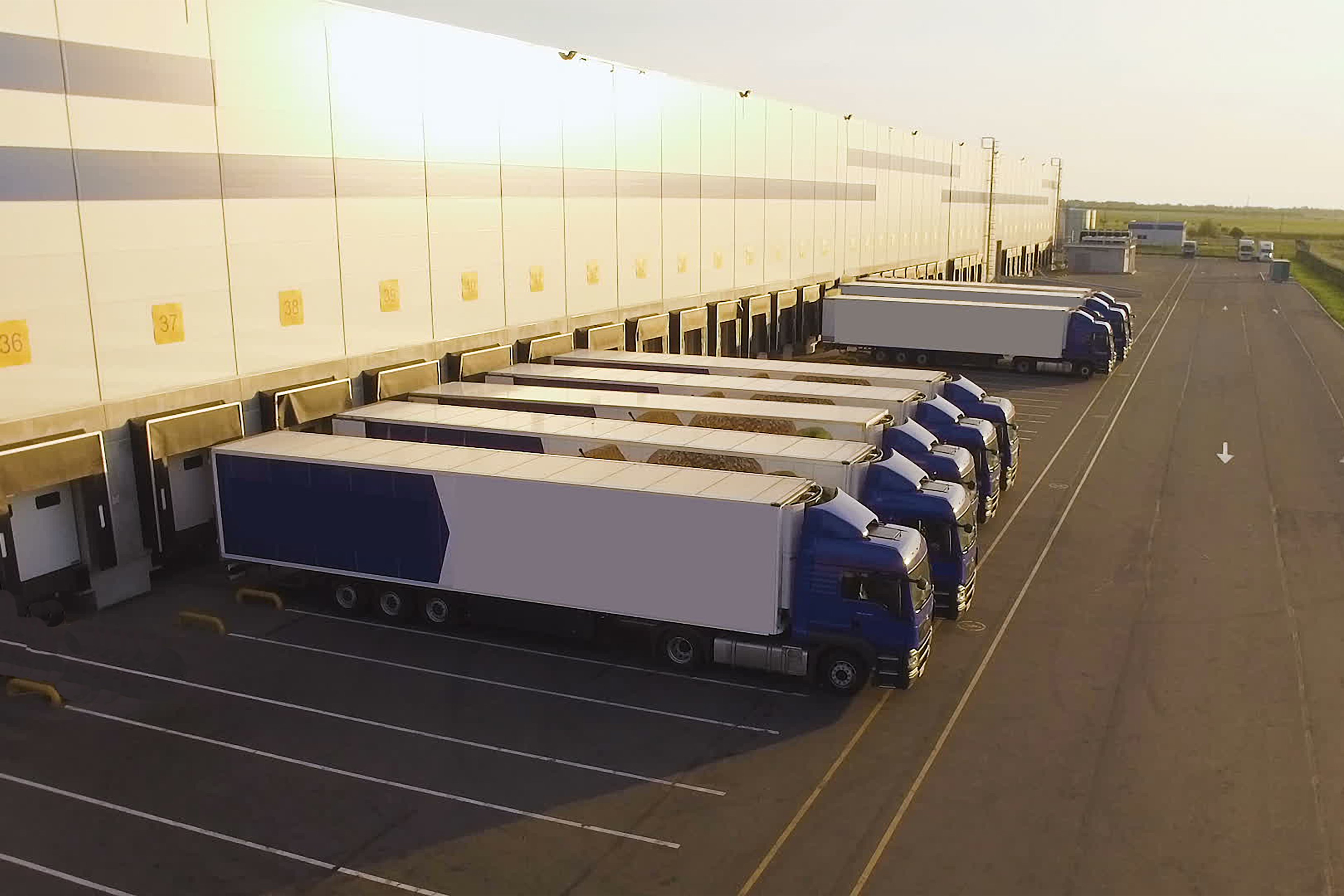 Tractor trailers being loaded behind factory.jpg