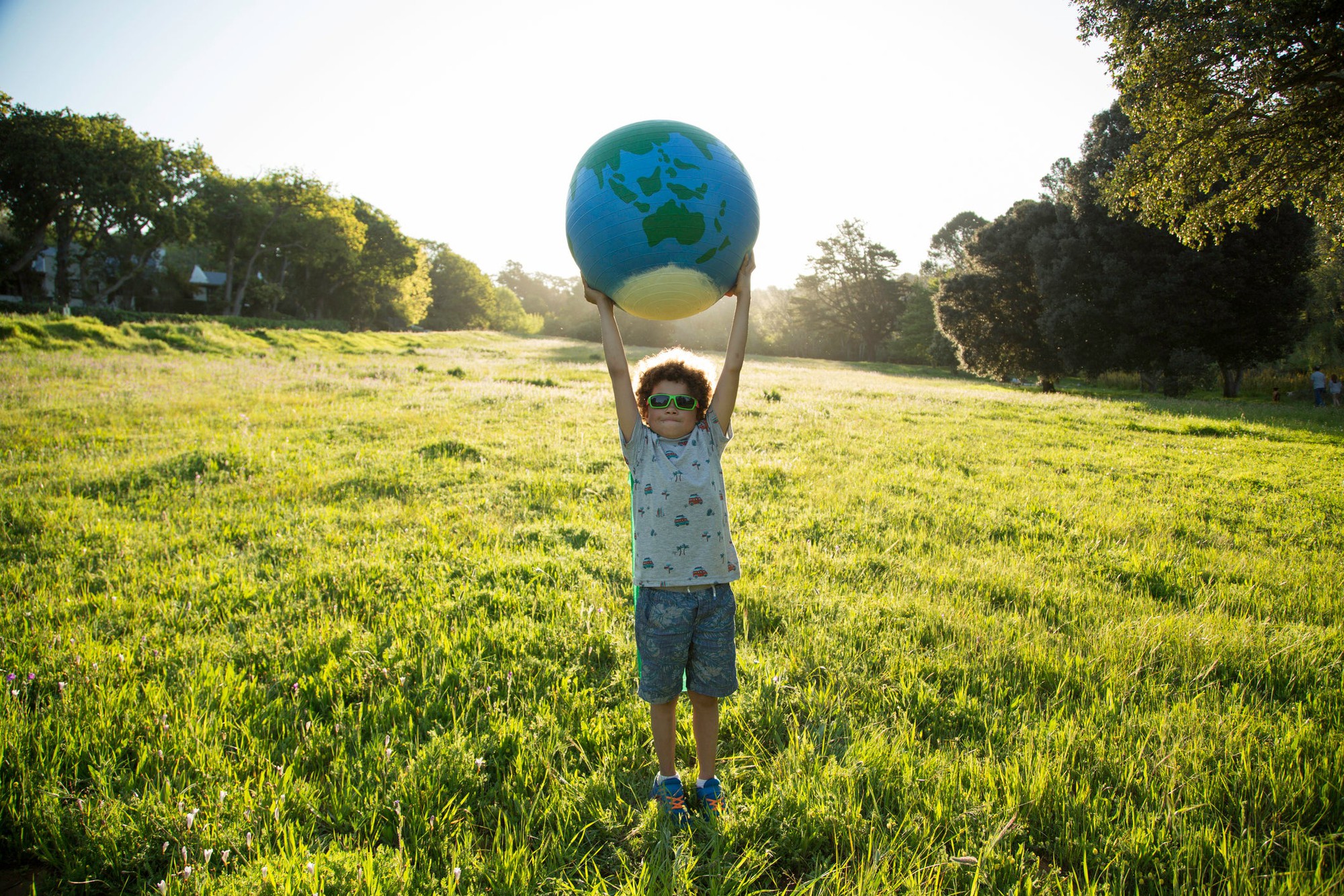 child_standing_holding_globe_outdoors