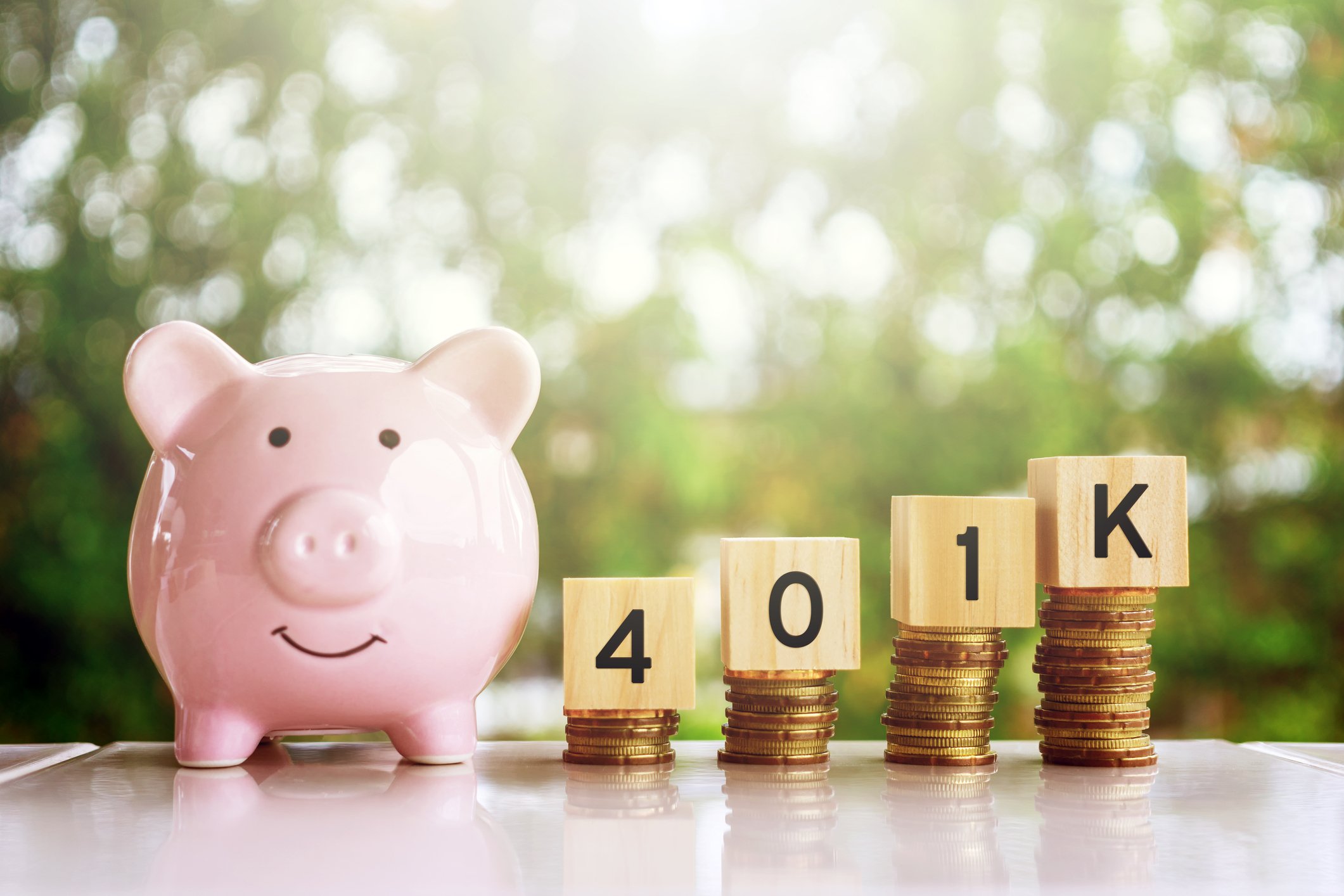 Smiling piggy bank next to rising stacks of coins topped with blocks saying 401k
