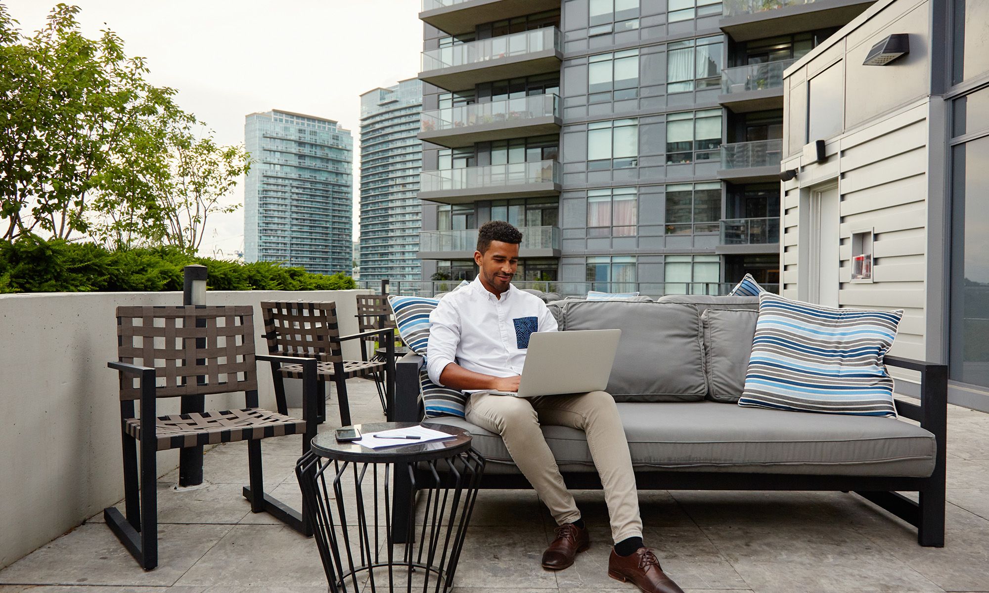 person on rooftop with laptop open on couch_AirBNB.jpg