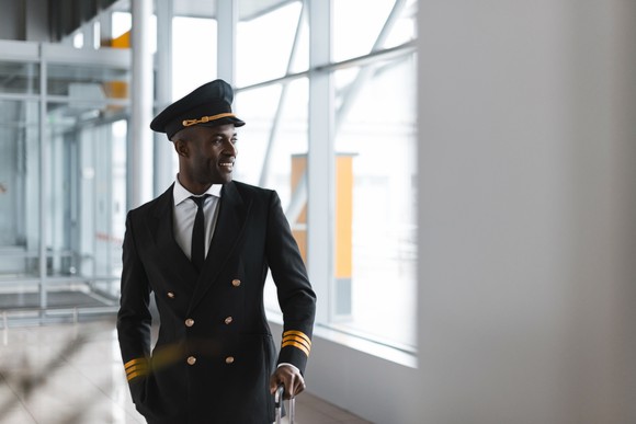 A smiling pilot in an airport concourse.