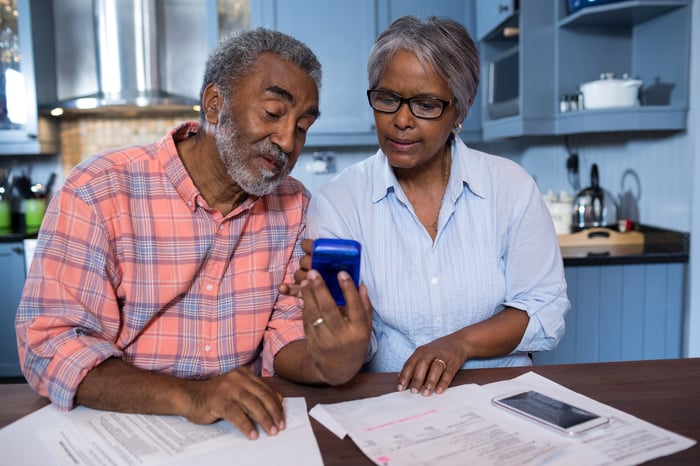 A mature African American couple consults a calculator while planning finances