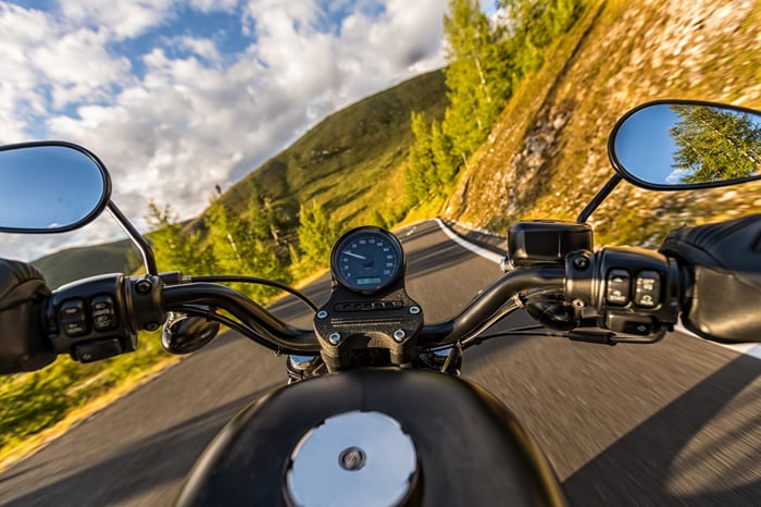 View of autumn countryside over the handlebars of a motorcycle.