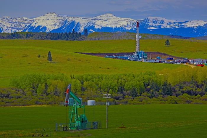 Oil wells against a mountain backdrop