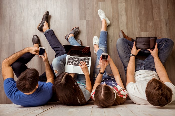 Group of young people on their smartphones, laptops, and tablet computers