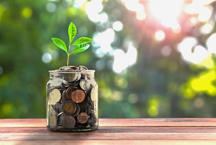 Jar full of coins with small plant growing out the top