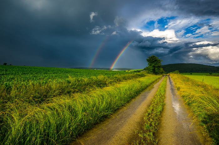 Rural road leading to a rainbow