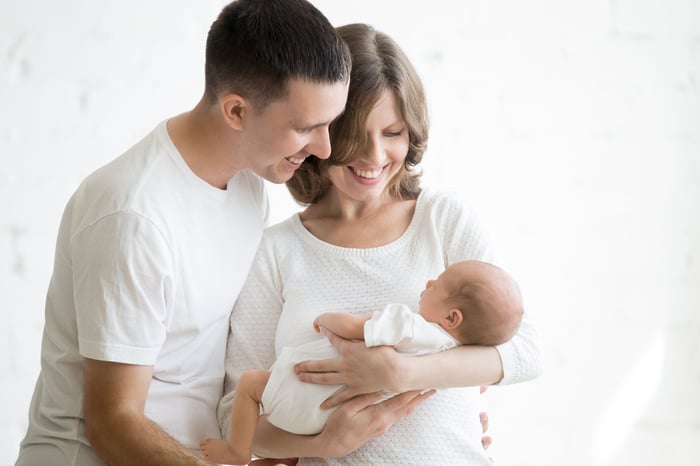 Father and mother holding newborn baby and smiling