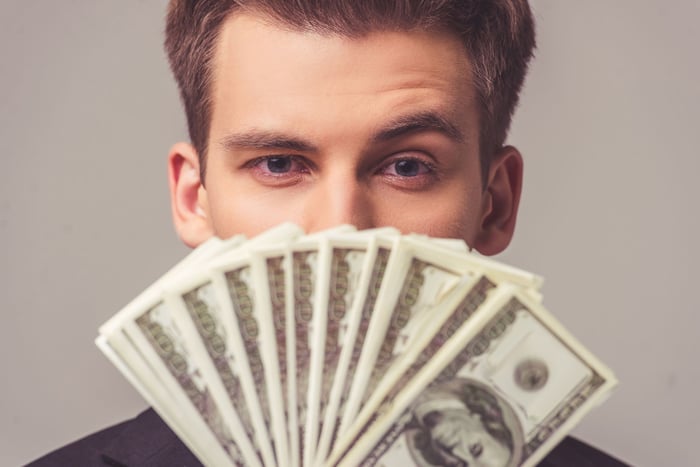 Young man holding cash in front of his face