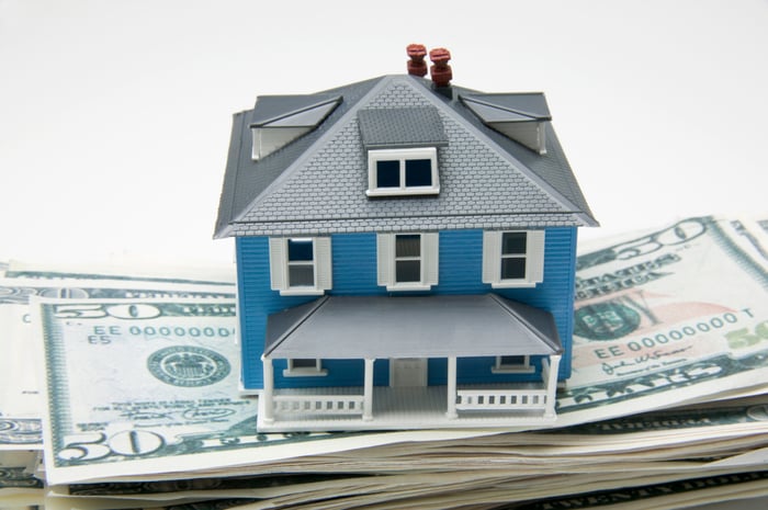 Small model house on top of dollar bills