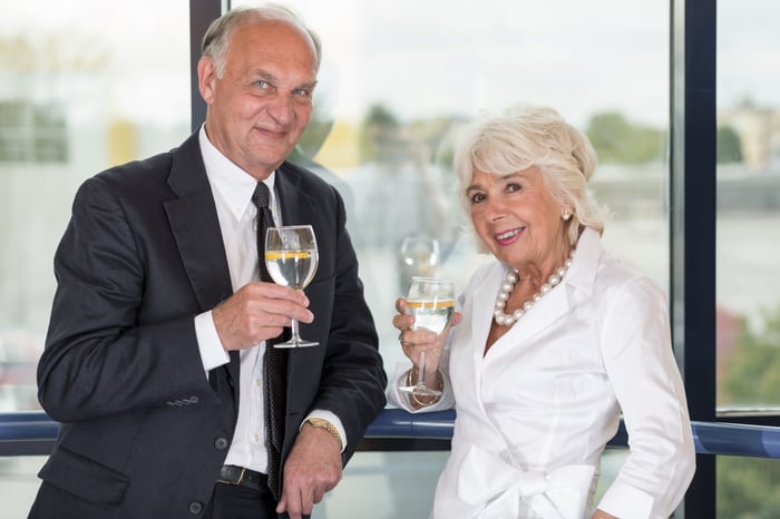 Senior couple standing by a window with champagne glasses.