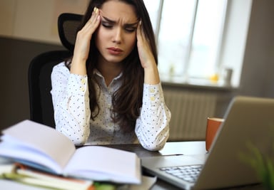 Woman looking perplexed with books and laptop -- GettyImages-506138806