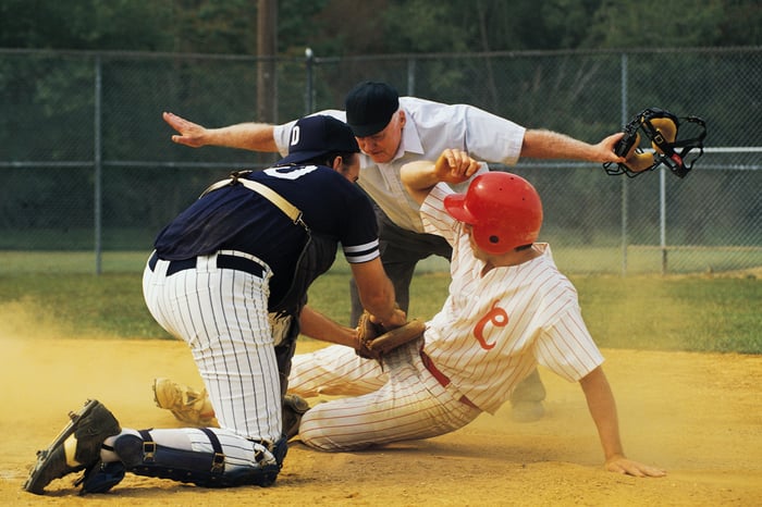 A baseball umpire, giving the "safe" signal when someone slides into home base