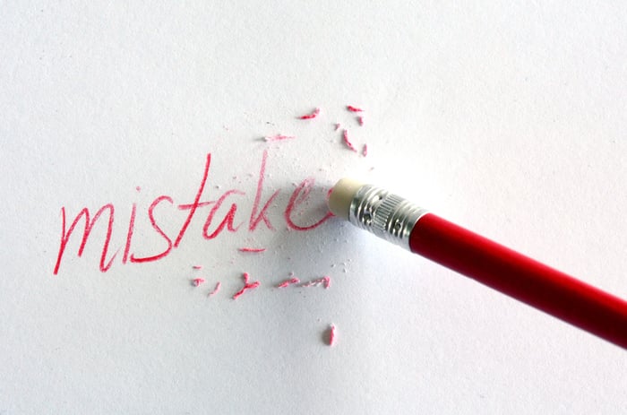 Pencil erasing the word mistake from a piece of paper.