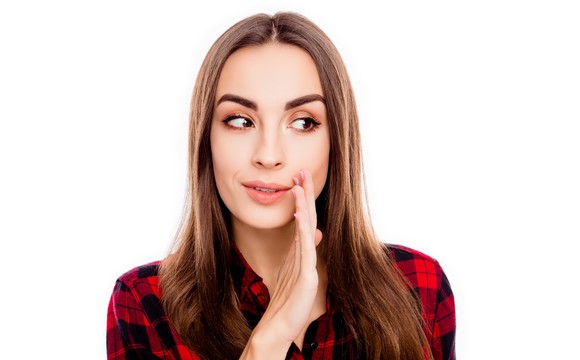Woman holding her hand up looking like she's about to tell a secret.