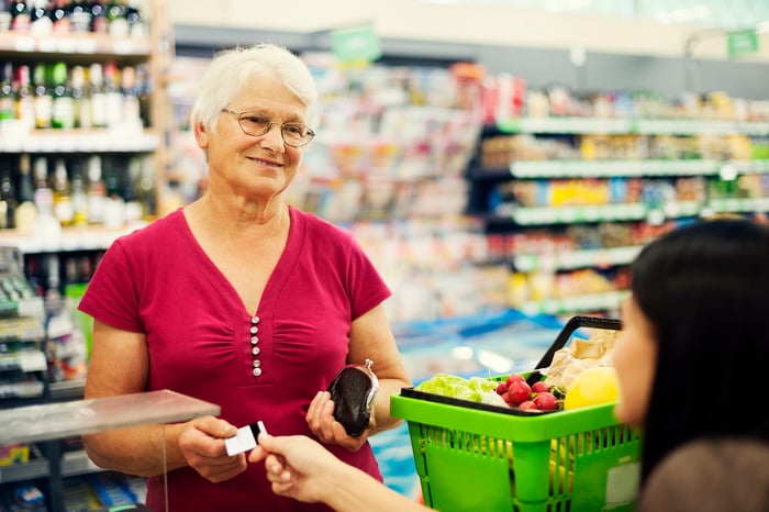 Elderly woman paying for groceries. 