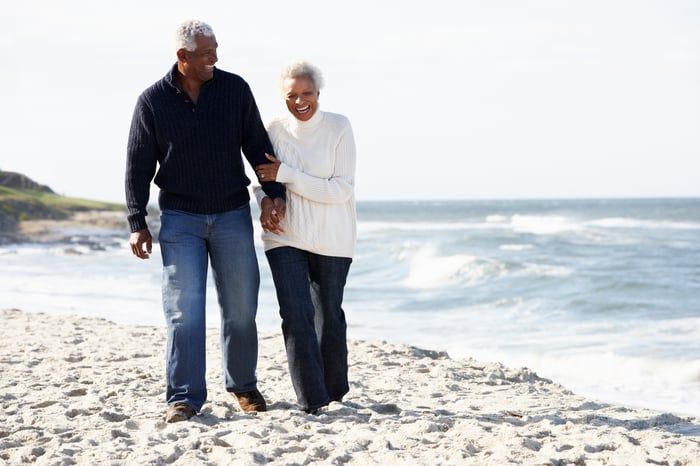 Senior couple on beach, holding hands.