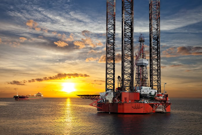 Oil platform and tanker ship on offshore area at sunset.