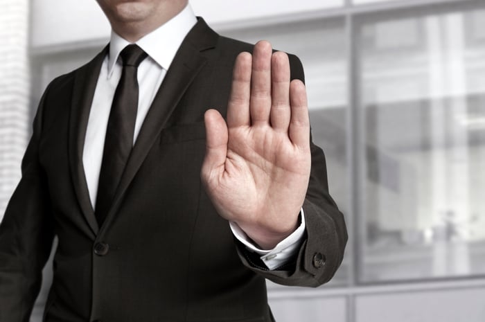 A businessman holds up his hand as if to say "stop."