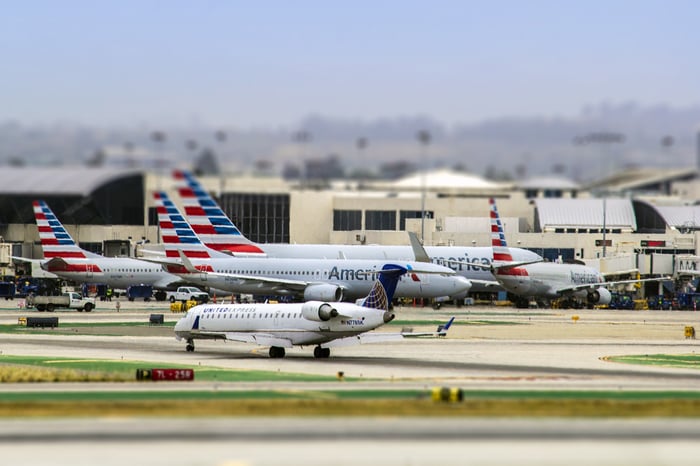 A United Airlines regional jet taxis in the foreground, with American Airlines jets in the background