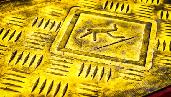 Caution sign with stick figure slipping.