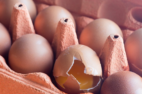 A cracked egg in a dozen egg container.