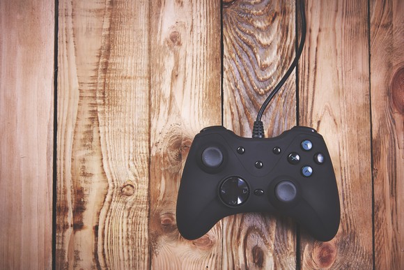 A video game controller resting on a wooden surface.