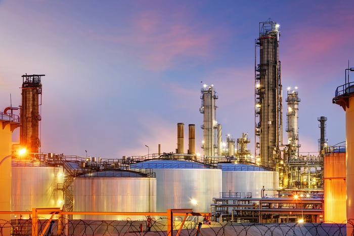 Oil refinery at twilight with oil storage tanks in front.